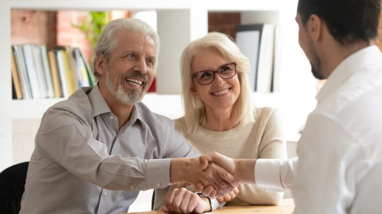 happy senior couple shake hands with lawyer