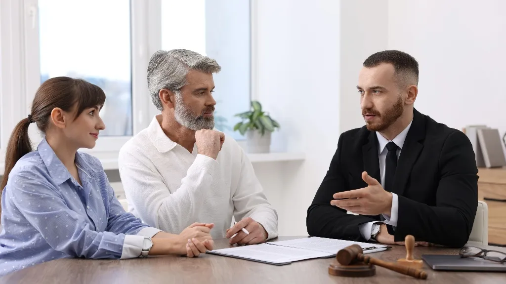 Three professionals engaged in discussion at a table with legal documents and a gavel.